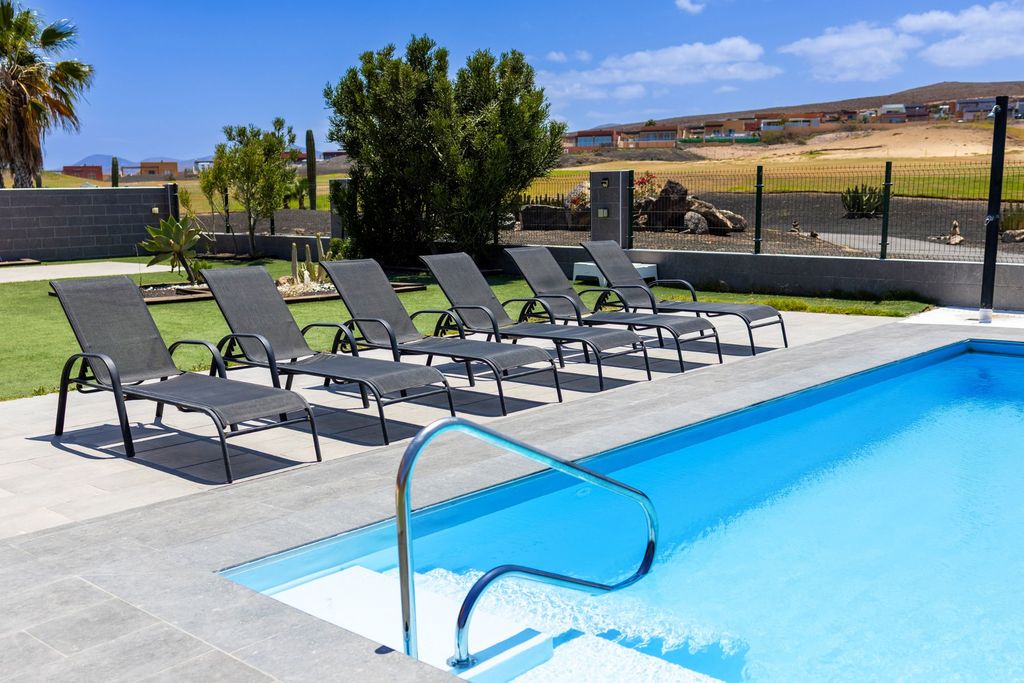 Piscina privada de Villa Magna con tumbonas y vistas al campo de golf en Caleta de Fuste, Fuerteventura