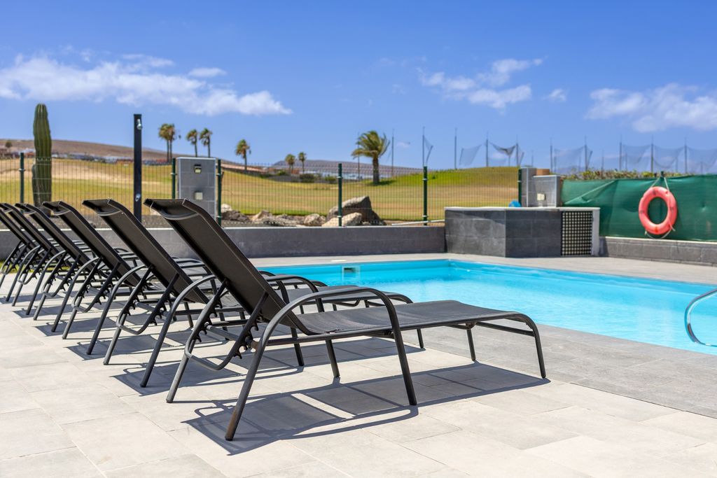Solárium con seis tumbonas junto a la piscina privada de la villa